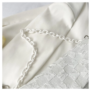 Close-up of white pleated crossbody bag featuring checkerboard texture and resin chain strap
