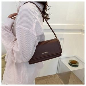 Side view of dark red leather shoulder bag on model showing size and compact structure