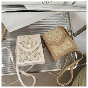 Detail of hand-woven crossbody bags with delicate floral embroidery in white and beige