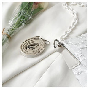 Detail of white lattice texture handbag with chunky chain strap and adjustable belt