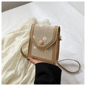 Detail of straw mini crossbody bag with daisy embroidery and leather trim finish