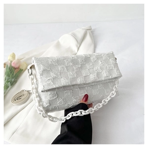 Detail of white checkered crossbody bag with chain strap and soft pleated fabric texture