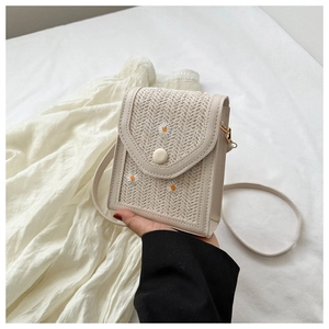 Detail of small woven shoulder bag with daisy embroidery and magnetic flap closure