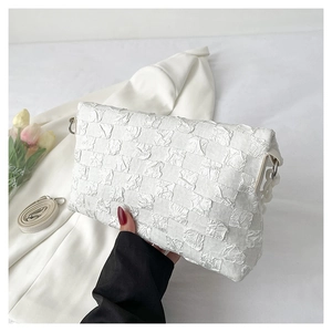 Detailed view of the white quilted fabric texture and silver hardware on a crossbody bag