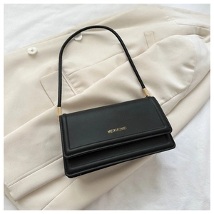 Close-up of black matte leather rectangular underarm bag with gold metal buckle detail