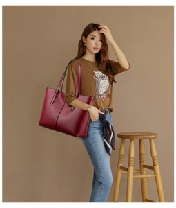 Detail shot of a large burgundy tote bag with pebble leather texture and double shoulder straps