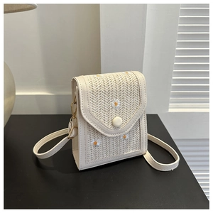 Detail of white woven crossbody bag with daisy embroidery and elegant gold hardware