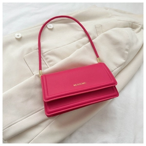 Detail showing fuchsia leather flap of the shoulder bag with gold logo and strap