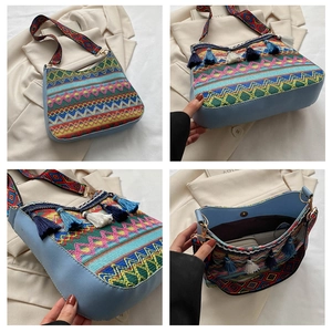 Detail view showing blue woven ethnic crossbody bag with tassels and geometric wide strap