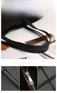 Detail of black quilted tote bag showing sturdy handles and silver metal zipper puller