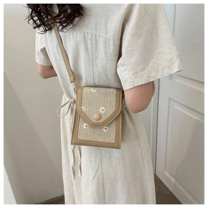 Straw woven shoulder bag with daisy embroidery shown on a person for size and scale