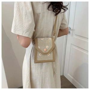 Detail of beige straw crossbody bag with white daisy embroidery and slim shoulder strap