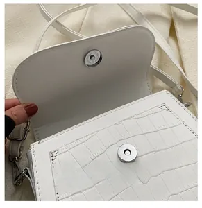 Dettaglio della borsa a tracolla bianca con motivo coccodrillo e chiusura magnetica