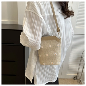 Gros plan de la broderie marguerite sur le sac seau en paille beige avec cuir