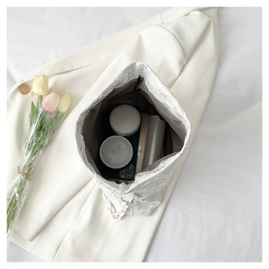 Top view of white textured bucket bag showing spacious interior with cosmetic items