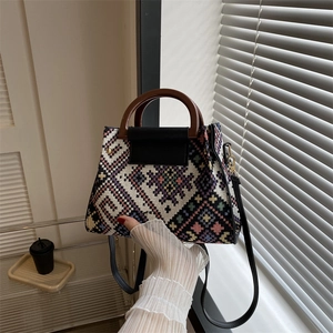 Detailaufnahme der Jacquard-Beuteltasche mit Vintage-Holzgriff und Klappe aus schwarzem Leder