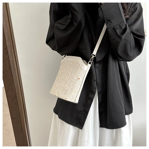 Détail de la broderie marguerite et de la paille tressée sur le sac seau bandoulière