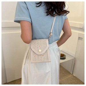 Detail of straw woven crossbody bag with daisy embroidery and slim leather strap