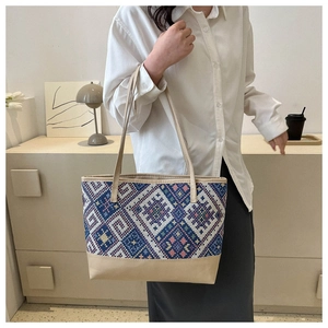 Detail of colorful geometric woven tote bag with durable cream leather shoulder straps