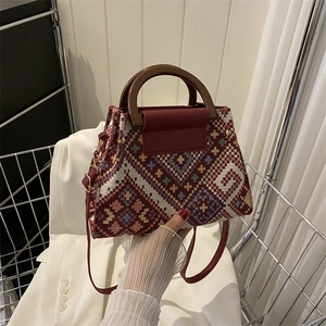 Detail des Vintage-Geometrie-Jacquard-Gewebes und rotbraunem Leder an der Beuteltasche