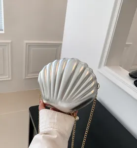 Close-up of silver shell-shaped bag with metallic texture, gold chain and pearl zipper