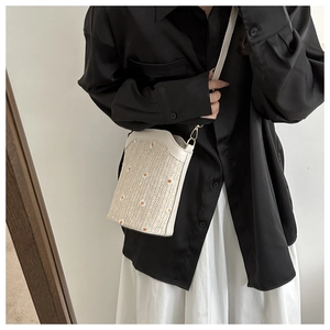 Détail du sac bandoulière en paille beige avec broderie marguerite délicate et crochet
