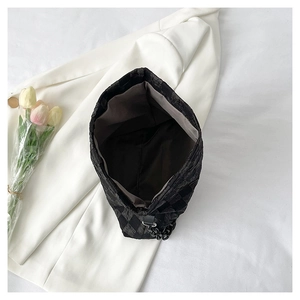Close-up of black quilted fabric bag with thick chain detail and spacious interior