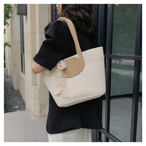 Detailed view of beige woven tote bag with lace bow and sturdy brown rope handles