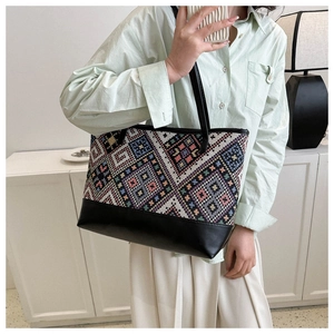 Detail of large tote bag with geometric woven pattern and slim black shoulder straps