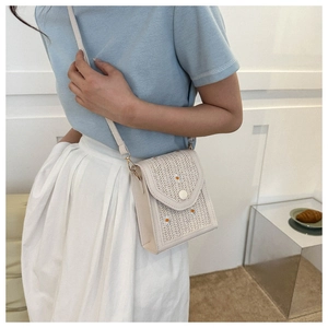 Detailed embroidery of white daisy flowers on a cream textured woven shoulder bag flap