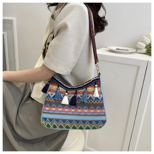 Detail of colorful woven bohemian shoulder bag with fringe tassels and patterned strap