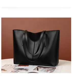 Detail view of a black faux leather tote bag with center stitching on a white surface