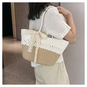 Detail of handwoven tote bag with white lace bow and wavy bicolor straw texture
