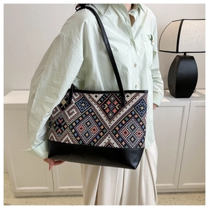 Detail of large tote bag showing woven geometric diamond pattern and black leather finish