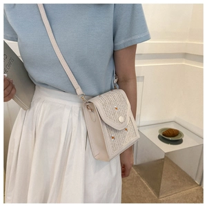 Close-up of woven straw handbag featuring delicate daisy embroidery and leather trim