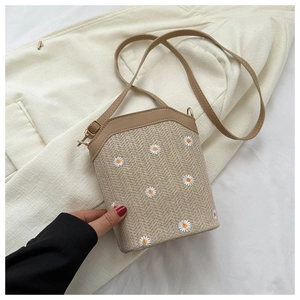 Gros plan d'un petit sac seau tissé avec broderie marguerite et bandoulière réglable
