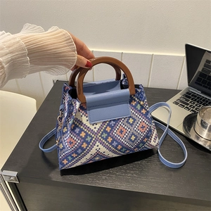 Detail der gewebten Boho-Beuteltasche mit Holzgriff und blauem Leder-Schultergurt