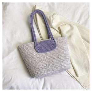 Detail of lavender and white woven tote bag with purple round handle on white fabric