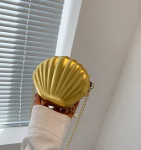 Close-up of gold shell crossbody bag with metal chain strap and pearl zipper puller