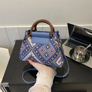 Detail der mehrfarbigen geometrisch gewebten Handtasche mit blauem Lederdeckel und Holzgriff