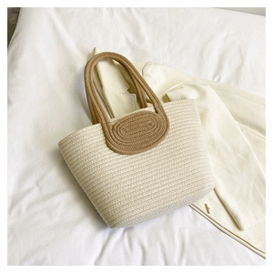 Close-up of cream woven tote bag texture with brown leather handle detail and contrast