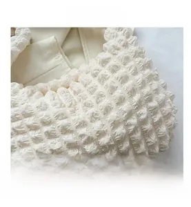 Detailed macro view of the cream popcorn bubble textured fabric on a stylish cloud bag