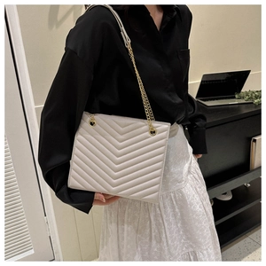 Quilted beige shoulder bag with gold chain strap shown on model for a chic look