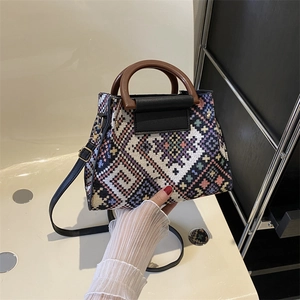 Close-up of geometric woven crossbody bag featuring a round wooden handle and gold hardware
