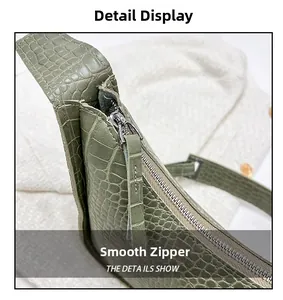 Detailed macro view of smooth silver metal zipper on sage green croc-embossed leather bag