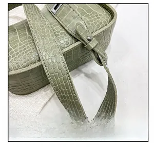 Detail view of the green crocodile texture leather strap with silver metal buckle