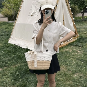 Two-tone woven straw shoulder bag with white lace bow detail for beach and summer travel