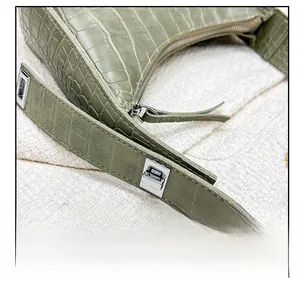 Close-up of green crocodile-embossed leather bag with polished silver-tone metal buckles