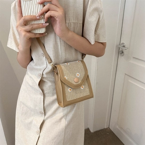 Straw crossbody bag with daisy embroidery and leather strap worn by a female model