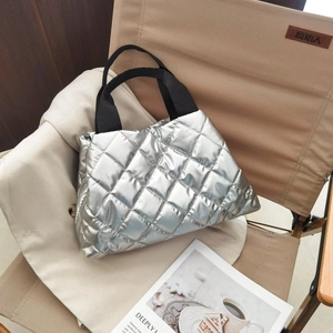 Détail du sac cabas matelassé argenté avec poignées en tissu noir sur une chaise